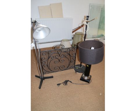 A black japanned table lamp, a studio lamp, one other lamp and a wrought iron spark guard