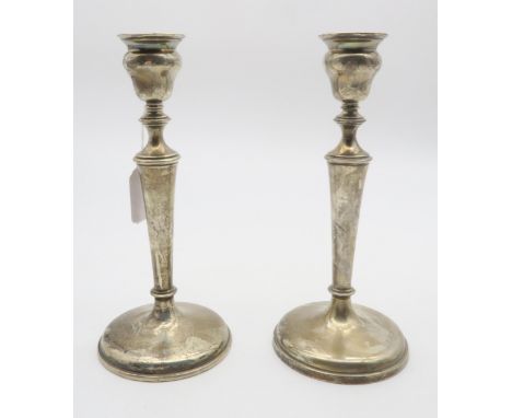 A pair of Edwardian silver candlesticks, of tapering form, the nozzles on capstan supports, on stepped circular bases (weight