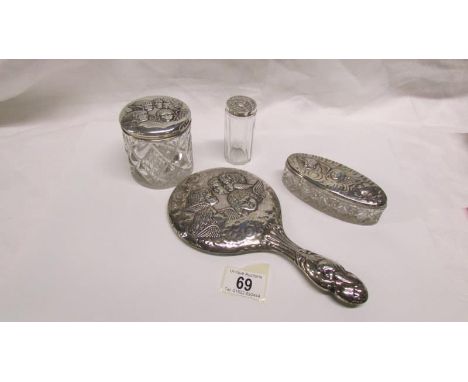 A silver backed hand mirror and 3 silver topped pots all embossed with cherubs, maker W J Myatt, Birmingham 1904