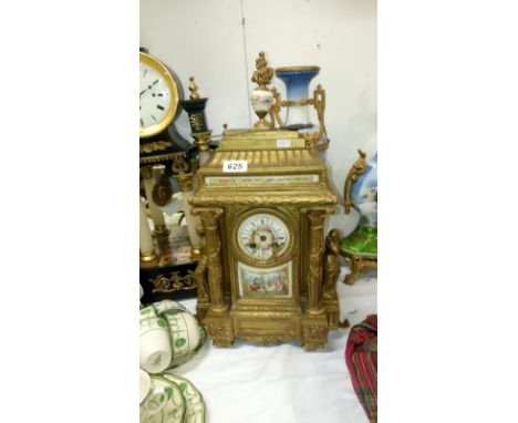 A gilded mantel clock with enamelled dial, porcelain panel and surmounted figures