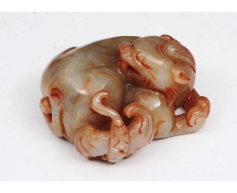 A CHINESE MOTTLED GREY, BROWN JADE FIGURE, of a temple lion, in curled recumbent position, 6cm long