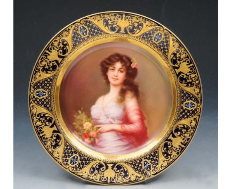 A LATE 19TH CENTURY VIENNA PORCELAIN CABINET PLATE, painted with a portrait of a young lady holding flowers within a gilt hei