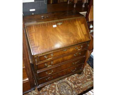 A reproduction Mahogany Bureau, the cross-banded fall front revealing an interior with two drawers and pigeon holes and havin