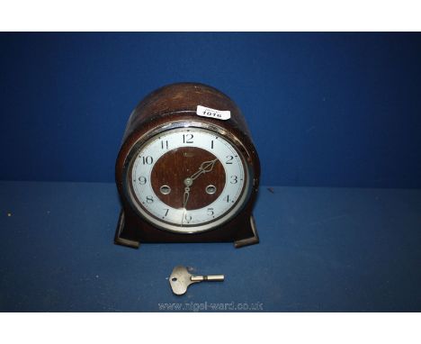 A wooden mantle Clock with a key.