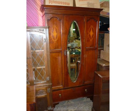 An Edwardian Mahogany Wardrobe, having light and darkwood stringing, oval inlaid details, oval bevelled mirror door, deep dra