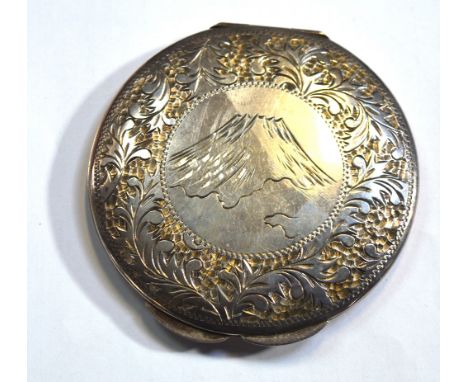 A silver compact with foliate design to the rim and central cartouche of a Japanese mountain marked to interior Sterling 950,