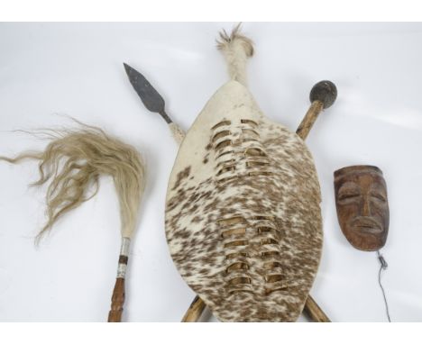 A Zulu shield with knobkerrie and spear together with an aboriginal boomerang a camba, a Sudanese leather wrapped spear and a