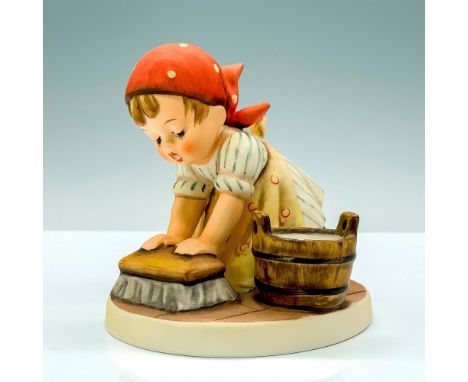 A figure of a young child in a blue striped dress, yellow apron, and red bonnet cleaning the floor. Goebel Hummel backstamp. 