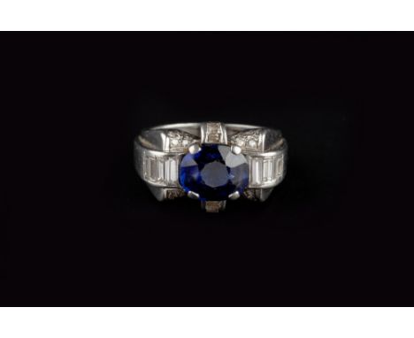 A SYNTHETIC SAPPHIRE AND DIAMOND DRESS RING, circa 1940, of odeonesque design, centred with an oval mixed-cut synthetic sapph