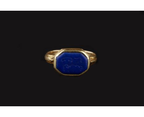A LAPIS LAZULI SIGNET RING, the octagonal lapis lazuli panel with Eastern inscription, in ropetwist edged collet setting, rin