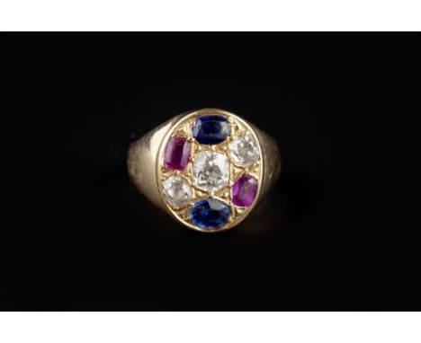 A RUBY, SAPPHIRE AND DIAMOND PANEL RING, the oval panel centred with a horizontal trio of old-cut diamonds, framed by pairs o