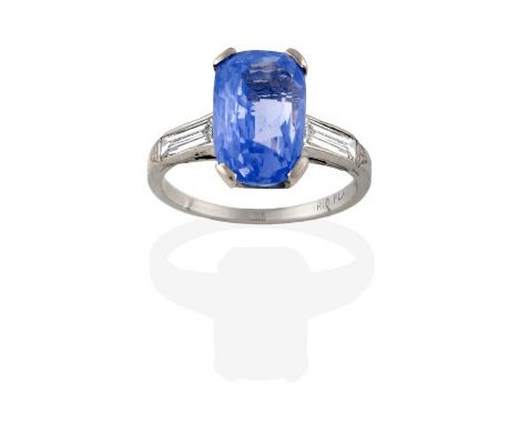 A Sapphire and Diamond Three Stone Ring, a cushion cut sapphire in a white claw setting, to baguette cut diamond set shoulder