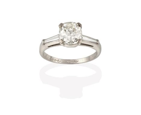 A Diamond Solitaire Ring, the cushion cut diamond in a white four claw setting, to tapered baguette cut diamond set shoulders