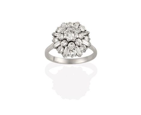 A Diamond Cluster Ring, the central raised round brilliant cut diamond within a border of smaller round brilliant cut diamond