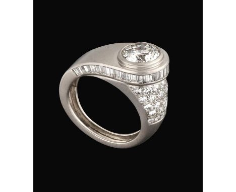 An Architectural Style Diamond Solitaire Ring, circa 1935, the raised round brilliant cut diamond in a baguette cut diamond f