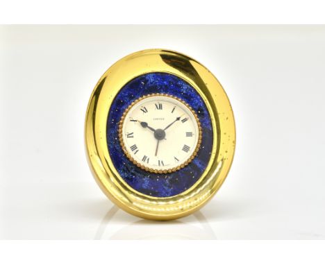 A CARTIER GILT METAL AND SIMULATED LAPIS LAZULI OVAL ALARM CLOCKThe signed circular cream coloured dial with black hands and 