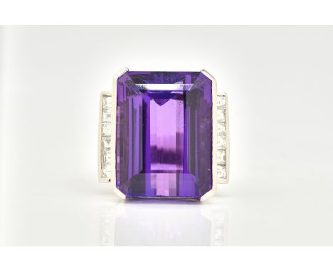 A WHITE GOLD, AMETHYST AND DIAMOND RINGMounted with the large cut cornered rectangular step cut amethyst between square cut d