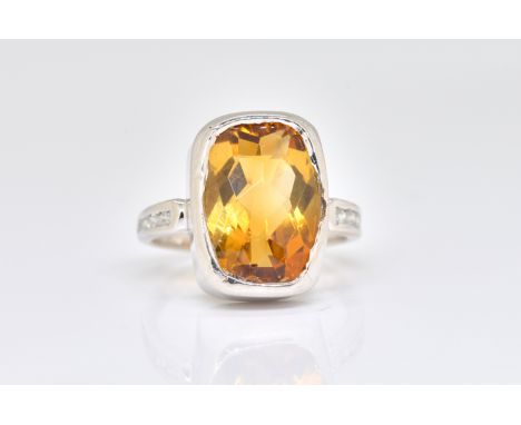 A CITRINE AND DIAMOND RINGBezel set with an oval-cut citrine, with channel set diamond shoulders, detailed 750, ring size P, 