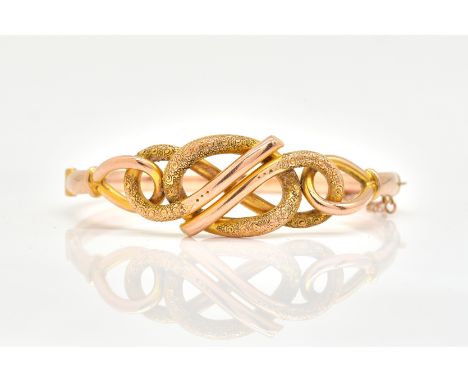 A 9 CT GOLD OVAL HINGED BANGLEThe front in an interwoven design, having a partly textured finish, on a snap clasp, Birmingham