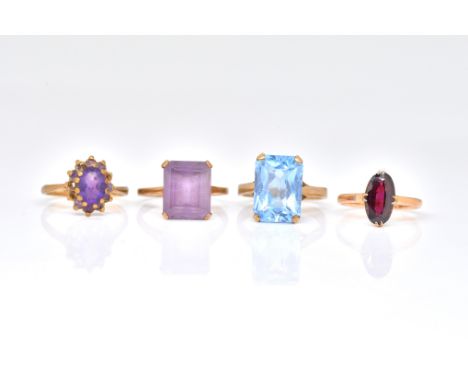 FOUR 9CT GOLD AND GEM SET RINGS (4)comprising, two amethyst rings, a pale blue synthetic gem set solitaire ring and a garnet 