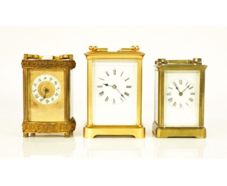 THREE BRASS CORNICHE CARRIAGE CLOCKS (3)Late 19th / Early 20th CenturyThe first with enamelled dial and Roman hours, twin bar