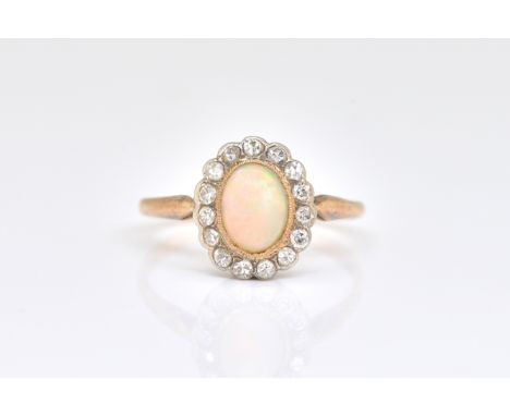 A GOLD OPAL AND DIAMOND OVAL CLUSTER RINGcollet set with the oval opal in a surround of circular cut diamonds, ring size N, g