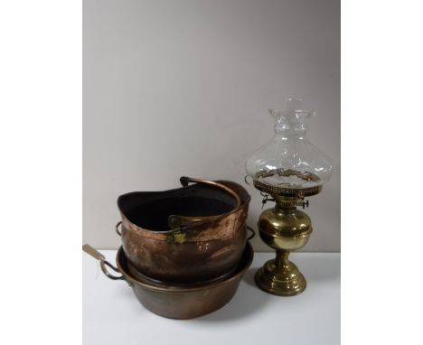 An antique copper twin handled pan together with a copper coal bucket and a brass oil lamp with glass chimney and shade