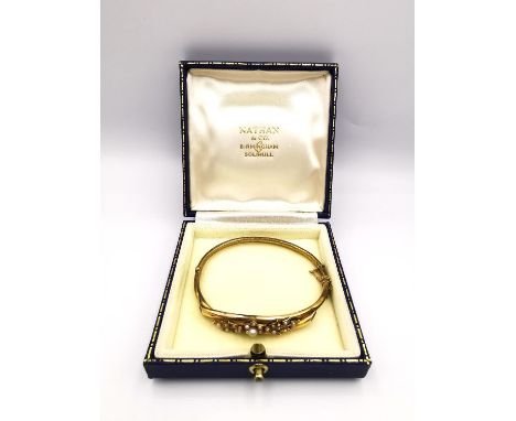 A Victorian 15 carat yellow gold and seed pearl floral design bangle, set with nineteen round seed pearls, cross over branch 