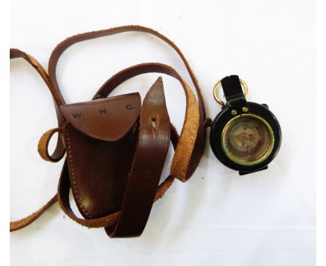 Military brass and black metal handheld compass in leather carrying case