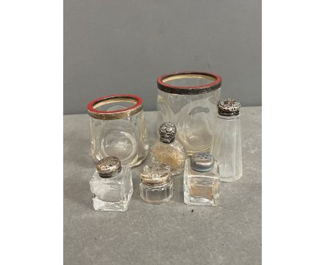 A selection of glass and white metal topped perfume bottles and enamel top jars, some silver