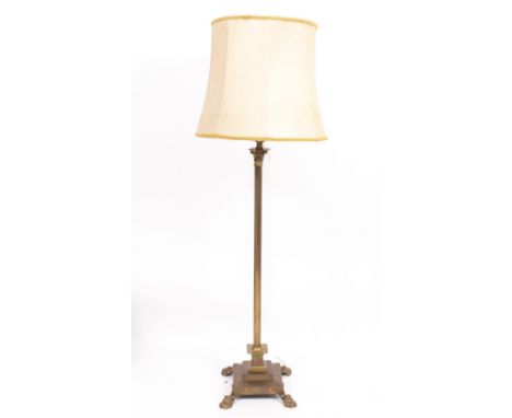 A BRASS STANDARD LAMP in the form of a Corinthian column on square spreading base terminating in pad feet, with cream coloure