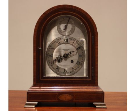 An early 20th century mahogany cased mantel clock, the arched case with oval fan inlay enclosing the 17cm silvered dial signe