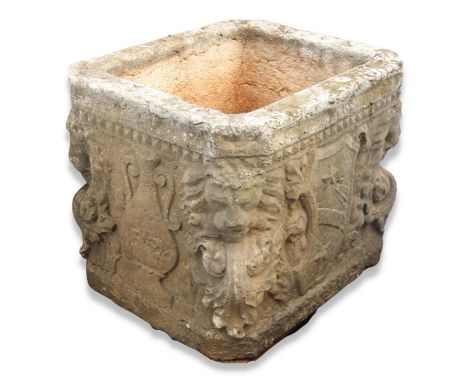 A 17th century style carved Istrian stone planter, of cubic form, with canted corners, carved with shield, mask and foliate d