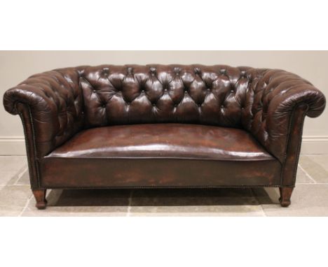 An early 20th century oak framed Chesterfield sofa, with typical deep set button back and arms, applied with peripheral stud 