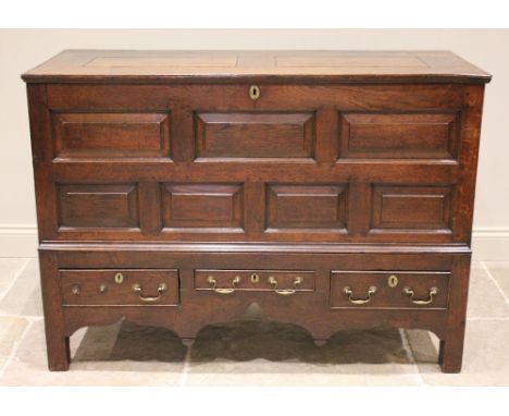 A mid 18th century oak mule chest, the hinged removable cover above an arrangement of five chamfered panels and three drawers