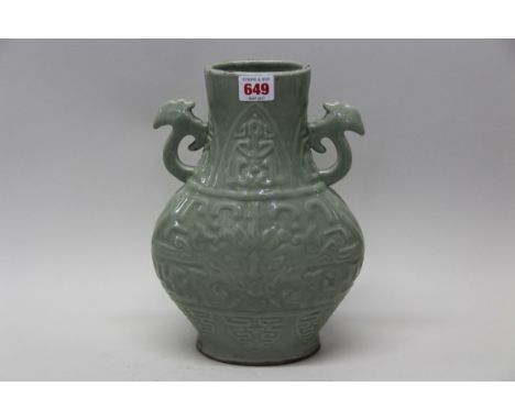 An antique Chinese celadon twin handled vase, partially drilled seal mark to base, moulded with stylized decoration, 28cm hig