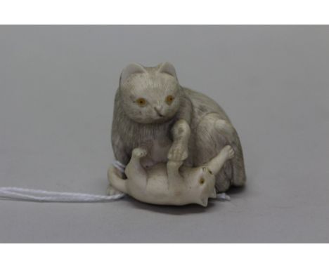 A Japanese carved ivory figural netsuke, Meiji period, of two cats, signed, 3.7cm high.