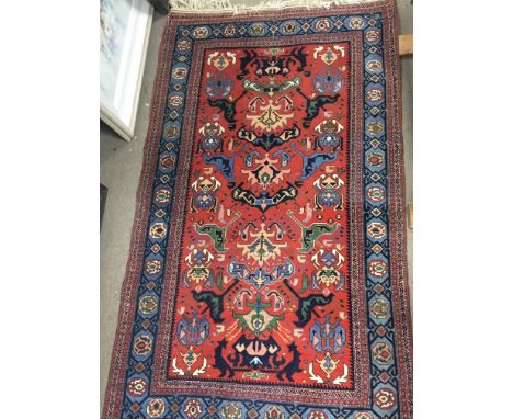 A hand knotted 20th Century Middle Eastern rug with a geometric pattern on a red ground with a light blue boarder size 170x10