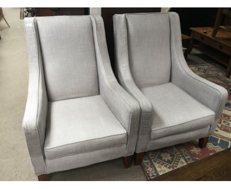 A pair of modern arm chairs upholstered in a light grey fabric.