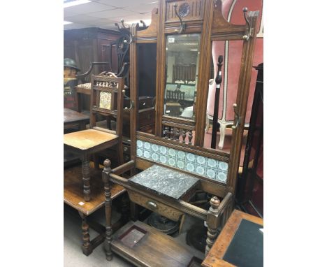 An Edwardian oak hall stand with a ceramic tile inset marble top and turned supports.