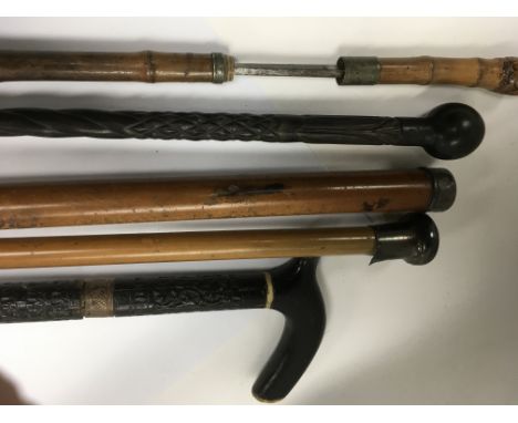 A bamboo sword stick and four other walking sticks