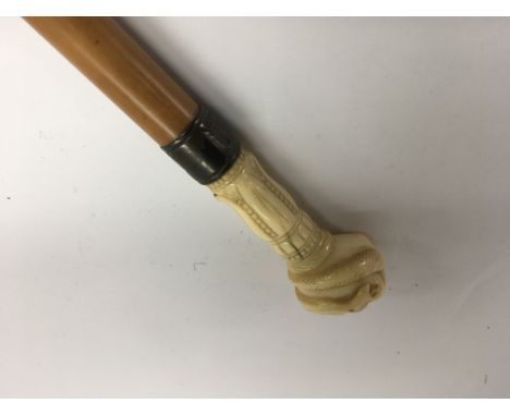 A Victorian walking stick the ivory handle in the form of a clenched fist with silver collar .