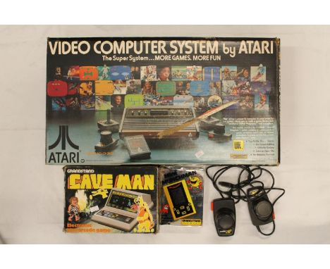 The Video Computer System by Atari model CX-2600 boxed, Grandstand Cave Man mini arcade game and another Mini Munchmen. 