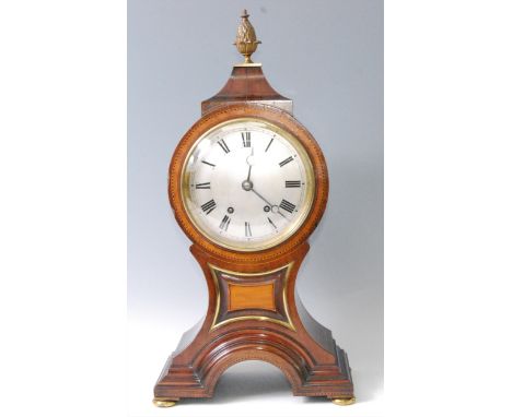 A late 19th century mahogany and inlaid balloon shaped mantel clock, having brass pineapple finial over unsigned silvered con