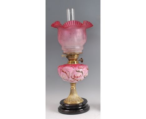 A Victorian brass pedestal oil lamp, having cranberry tinted and acid etched shade over moulded pink glass font, the whole ra