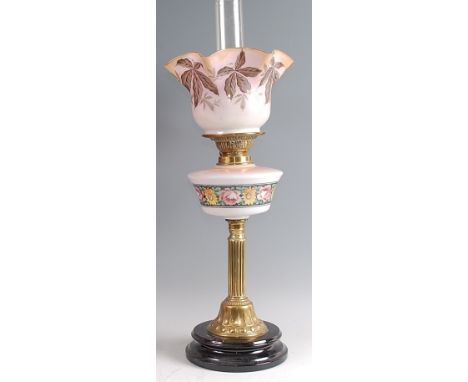 A late Victorian brass pedestal oil lamp, having opaque glass shade polychrome painted with leaves, with further opaque glass