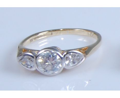 An 18ct yellow and white gold diamond three-stone ring, featuring a centre round brilliant cut diamond with a pear cut diamon