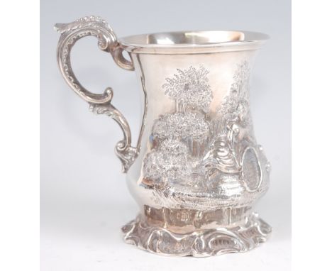 An early Victorian silver christening mug, the whole chased with figures playing in a parkland setting, having flying S-scrol