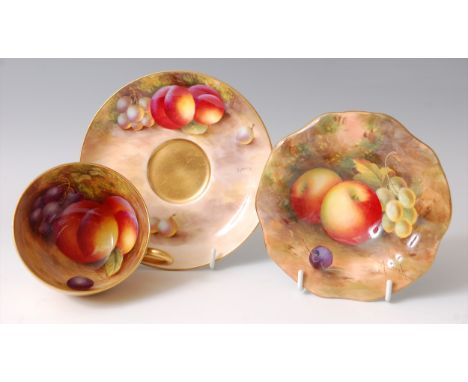 A Worcester porcelain teacup and saucer, each decorated with fruit on a mossy bank by Harry Ayrton, the cup with gilt exterio