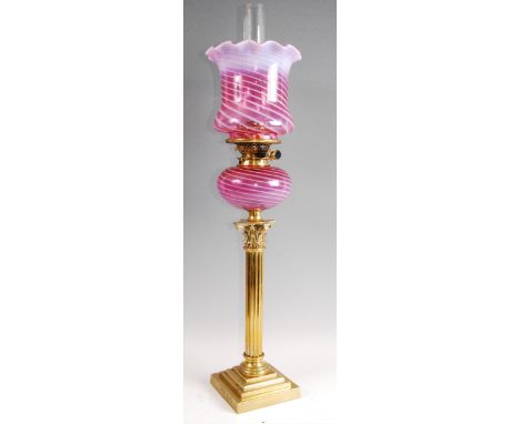 A Victorian lacquered brass pedestal oil lamp, having vaseline tinted cranberry glass shade with handkerchief rim, with a mat